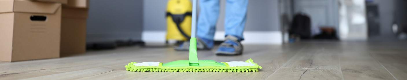 Close-up of professional cleaner washing floor with green mop. Man in working uniform. Han