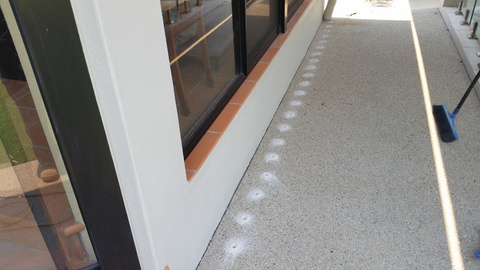 Professional drill-and-inject termite treatment points along a concrete building perimeter