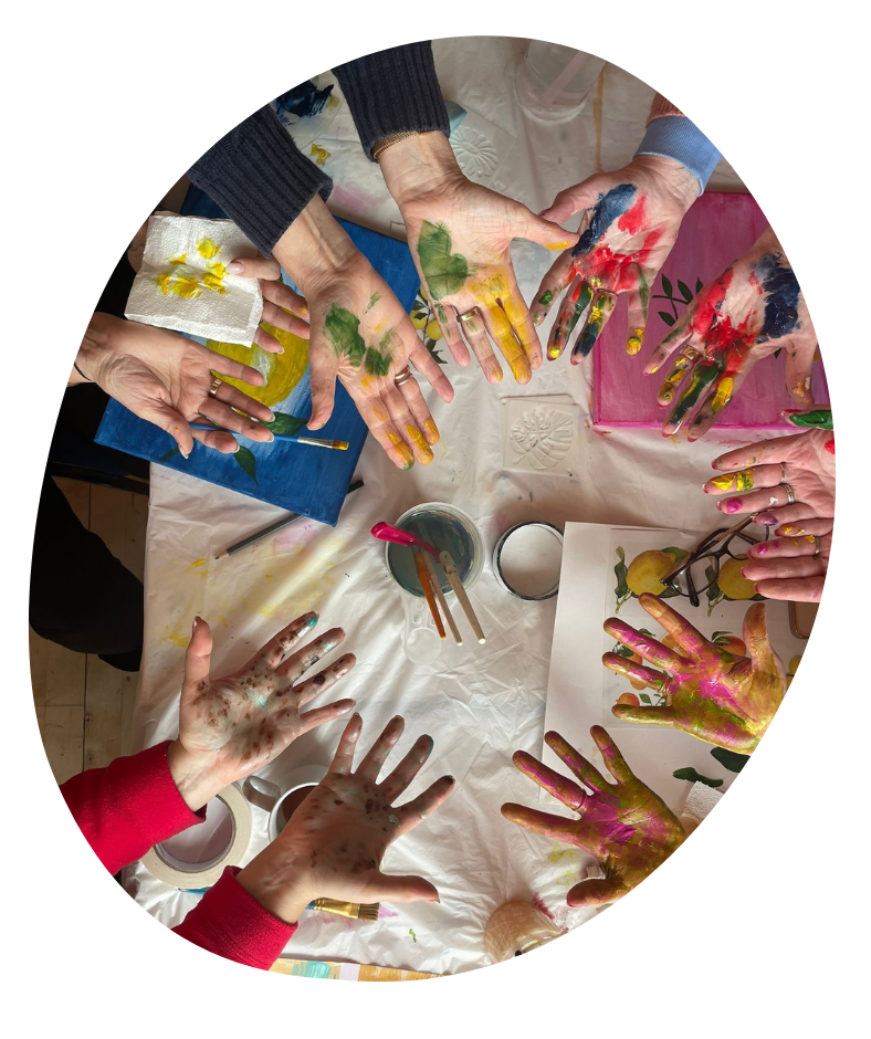 A picture taken from above of a community of women showing their paint covered hands.