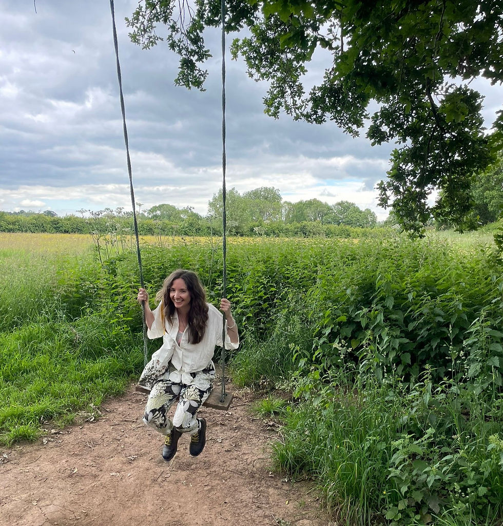 Happy, smiling woman joyfully playing on a tree swing in a field.