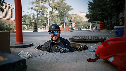 A Young Electrical electrician stands in a manhole performing preventative maintenance at City Hall in Windsor, ON