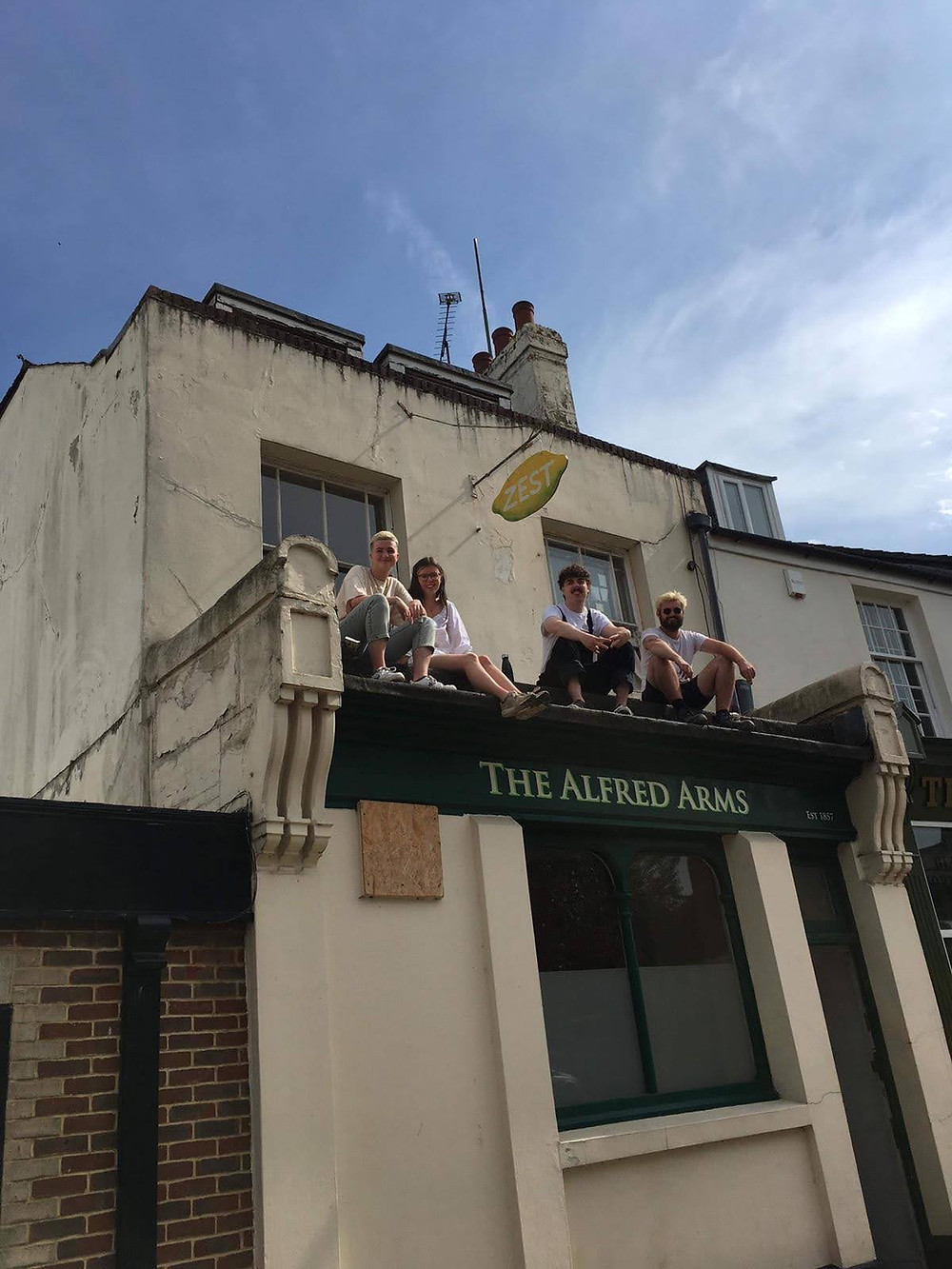 A group of four people sat on the roof of a building called The Alfred Arms in Southampton. Above this building is their art studio.