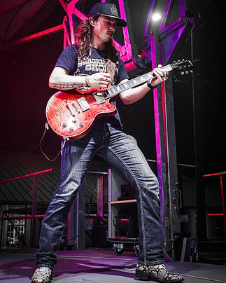 alt=_Dawson Stepp with electric guitar performing on stage with pink and purple stage ligh