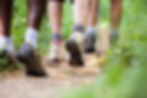 group of men and women during hiking excursion through the woods, feet walking in queue along trail