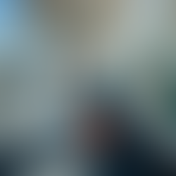 A woman with a backpack and orange suitcase walks along an airport jet bridge, smiling. A plane and blue sky are visible outside.