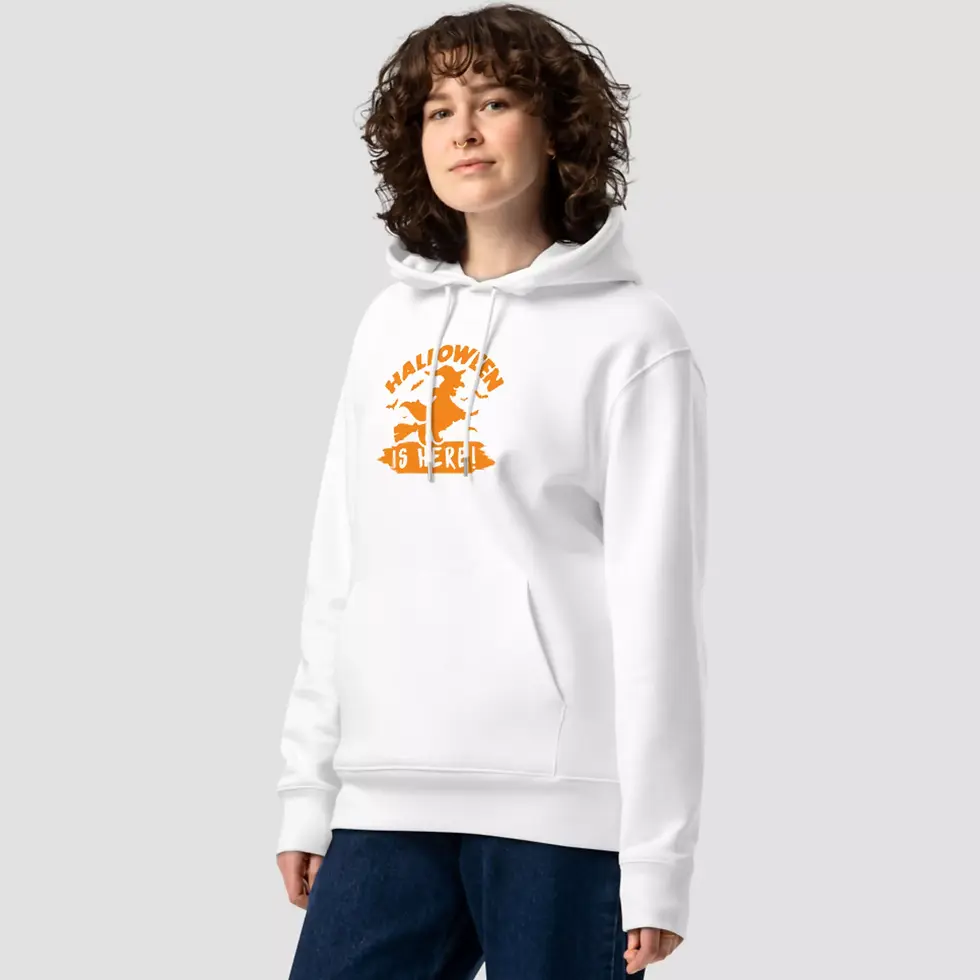 Sweat à capuche sorcière is here Halloween blanc. Haut unisexe mis en valeur par une femme. Design imprimé sur un coton bio.