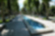 long narrow blue pool in the center of a tree-lined walkway in a park in Caramanico Terme Italy