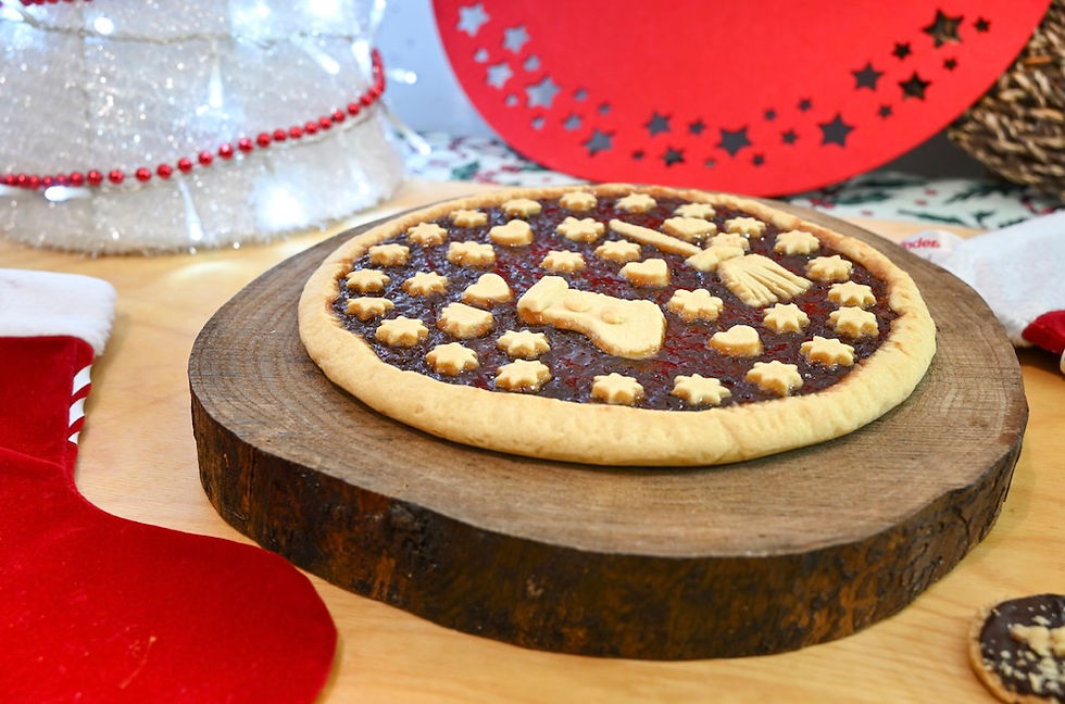 traditional italian befana dessert cookie decorated with a witch broom and christmas shapes on a wooden circular board with christmas decor surrounding it