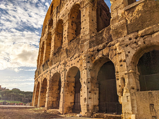 Ancient outer walls of the Colosseum in Rome with an orange glow from the sunset
