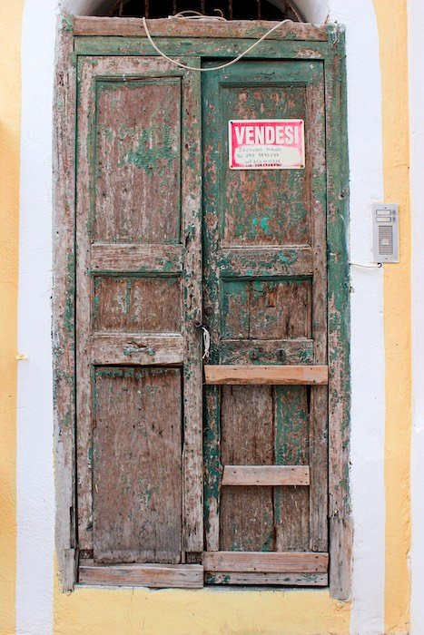 old weathered door with an Italian for sale sign on it