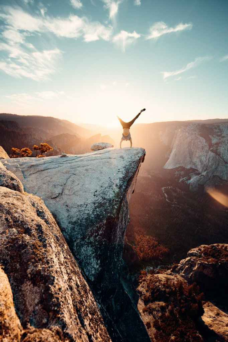 canyon view with someone doing a handstand at the end of a ledge