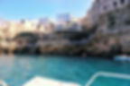 white boat on aqua water by a sea cave in Polignano A Mare Italy