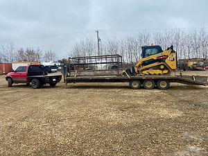 dodge flat deck truck with a pipe stand and skid steer on a gooseneck trailer