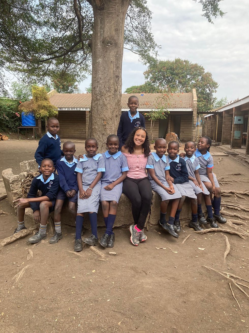 Amondi sitting by a tree with several students