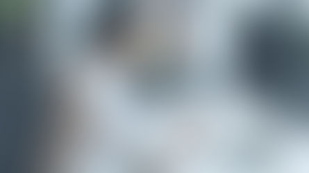 A woman sitting in front a computer screen and looking down at her phone