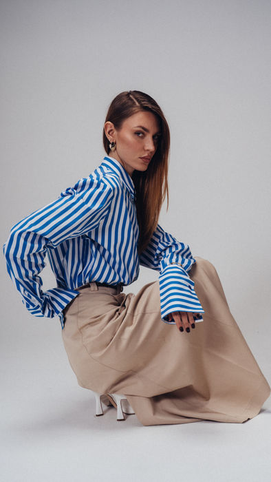 Studio fashion portrait featuring oversized striped shirt and tailored styling