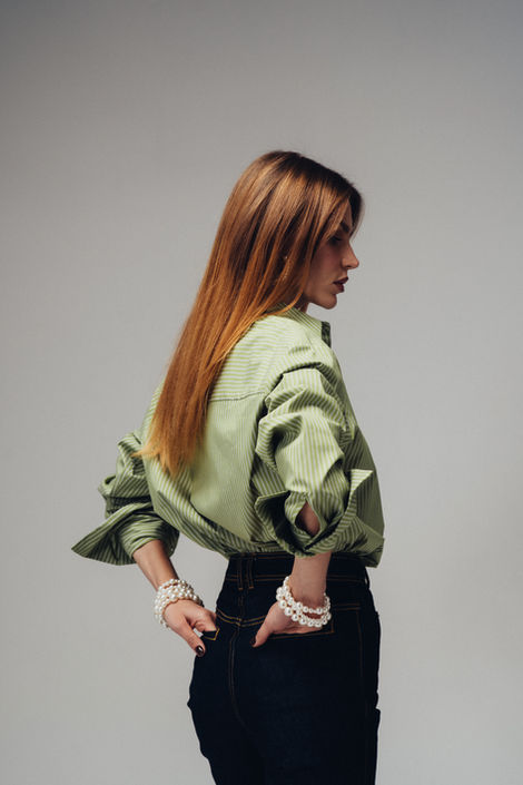 Fashion lookbook portrait of model in oversized green shirt and dark trousers