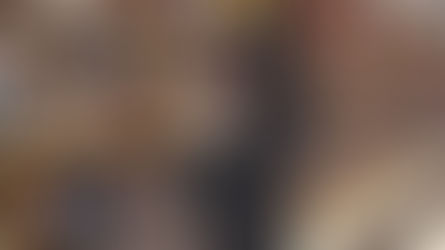 Mulher procurando livros em livraria, segurando alguns títulos com braço esquerdo.