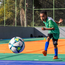 #ParaTodosVerem: Garoto uniformizado chutando uma bola em uma quadra.