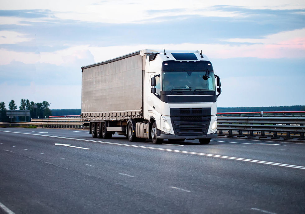 A modern truck with a tilt semi-trailer transports cargo along the highway in the evening