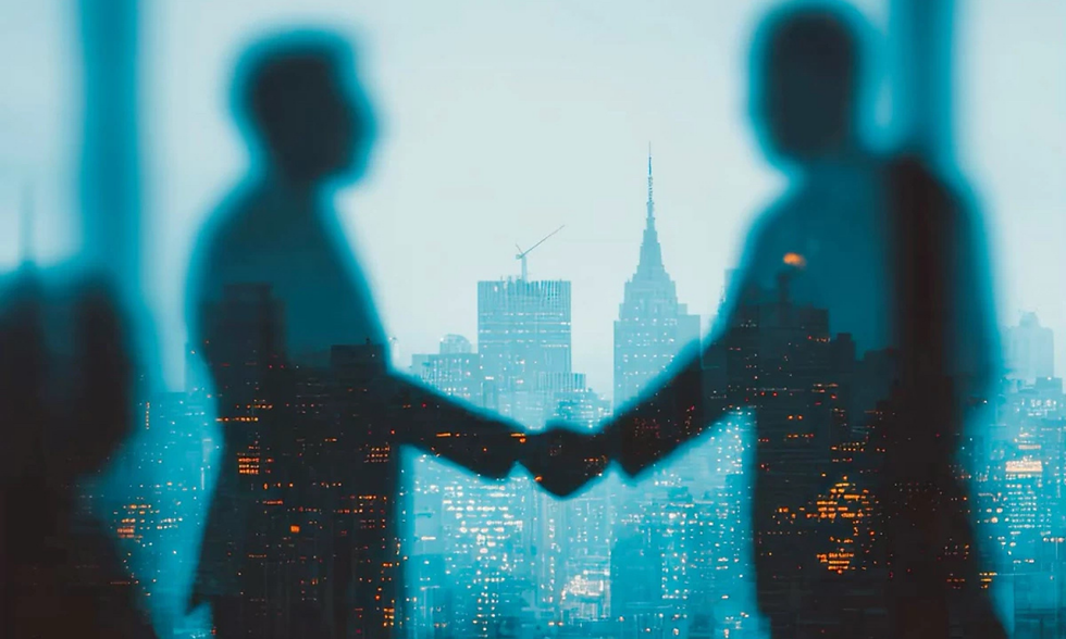 Two blurred silhouettes shake hands against a blue city skyline with lit buildings and a tall spire at dusk.