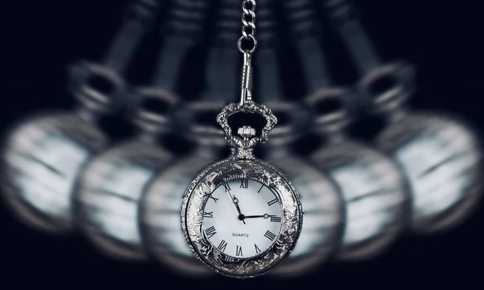 Pocket watch hanging against a dark background, with blurred mirrored copies; white face shows QUARTZ and Roman numerals.
