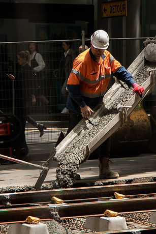 Construction worker pouring concrete in high-vis uniform, building law, building legal aid, construction law, construction business legal aid