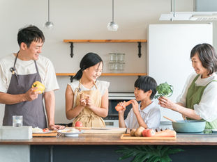 台所で家族4人が野菜を持って調理している