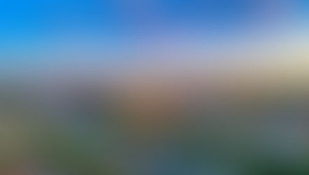 Skyline of Nashville at sunset, with downtown skyscrapers glowing in warm light above the Cumberland River, multiple bridges crossing the water, and colorful clouds in a blue and orange evening sky.