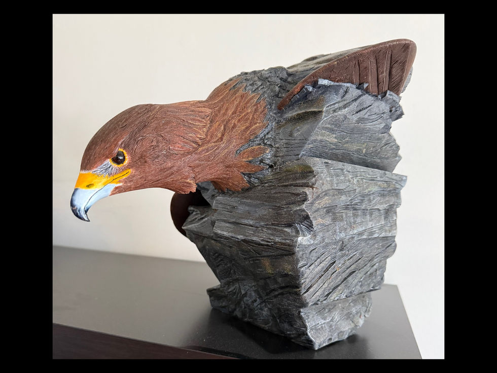 Sculptural wooden golden eagle coming through stone cliff face artwork