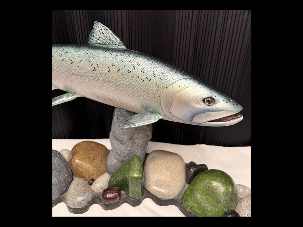 Salmon sculpture emerging above carved river stones in dynamic curved composition