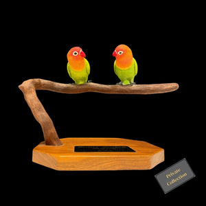 Two hand-carved lovebirds perched on a wooden branch with bright green, orange, and red plumage