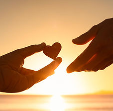 Deux mains devant un couché de soleil avec un coeur