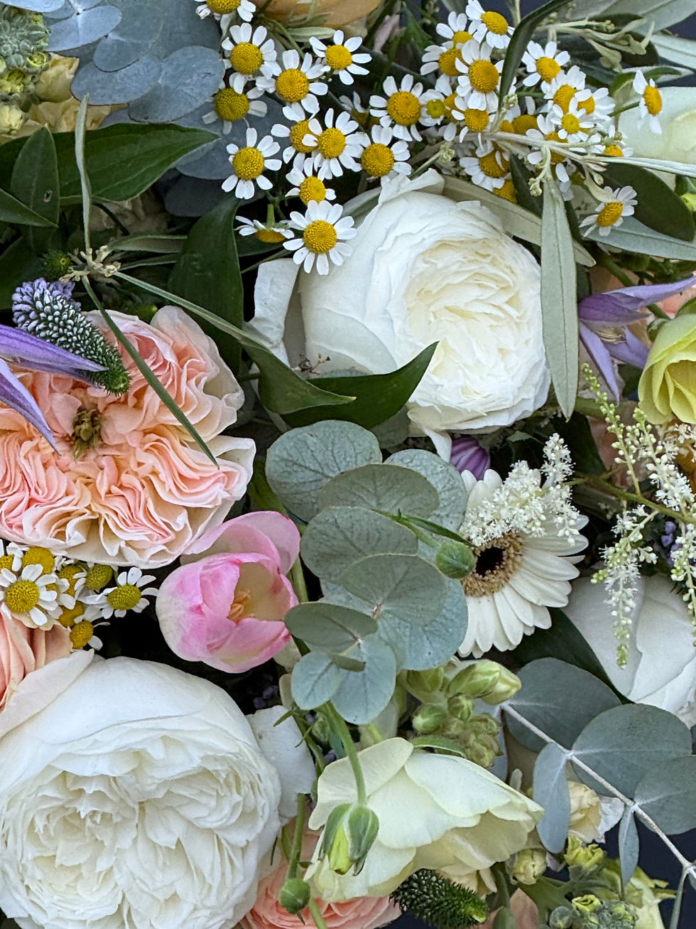Garden-style bridal bouquet with pastel flowers, chamomile, roses and natural movement.