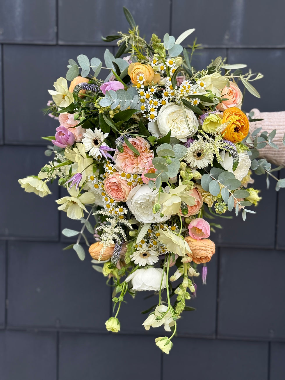 Finished bridal bouquet in a soft English garden style with seasonal flowers and flowing movement.