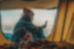 Man sitting on the ground near a tent on his cell phone