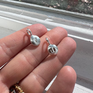 F U initial letter charms in silver on a hand