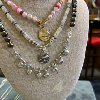 3 beaded necklaces on a bust with letter charms hanging from the charm necklace