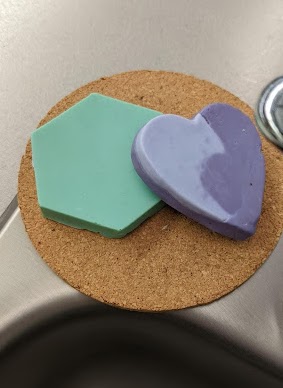 a blue hexagon and a dual tone purple heart on top of a cork coaster