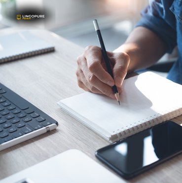 Người viết ghi chú trong sổ với laptop và điện thoại bên cạnh, thể hiện chương trình của LingoPure giúp nâng cao kỹ năng viết và giao tiếp tiếng Anh trong môi trường doanh nghiệp.