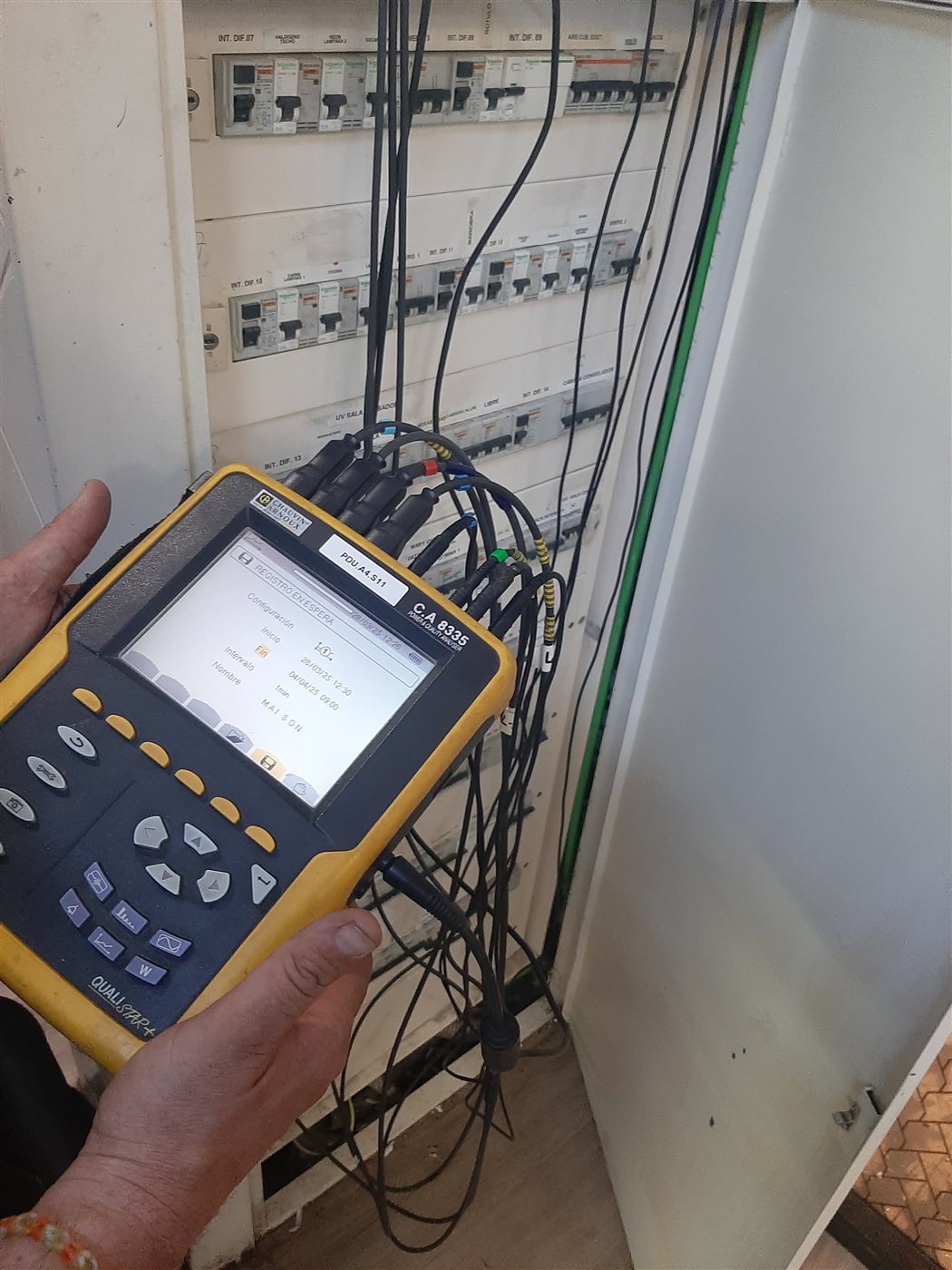 Mediciones eléctricas con instrumento de comprobación en un cuadro, durante un trabajo de Luz y Chispas