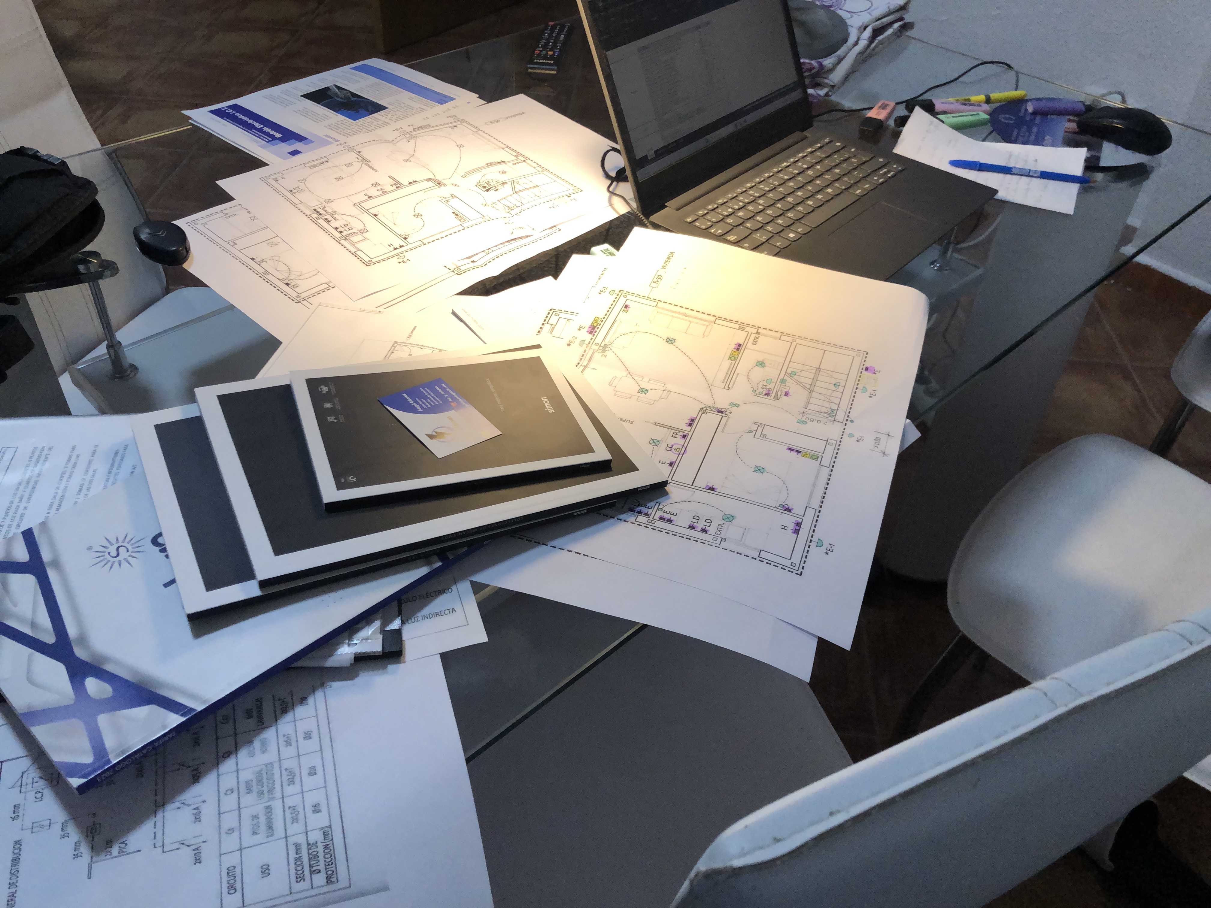 Planos de instalaciones eléctricas y documentación de obra sobre una mesa de trabajo