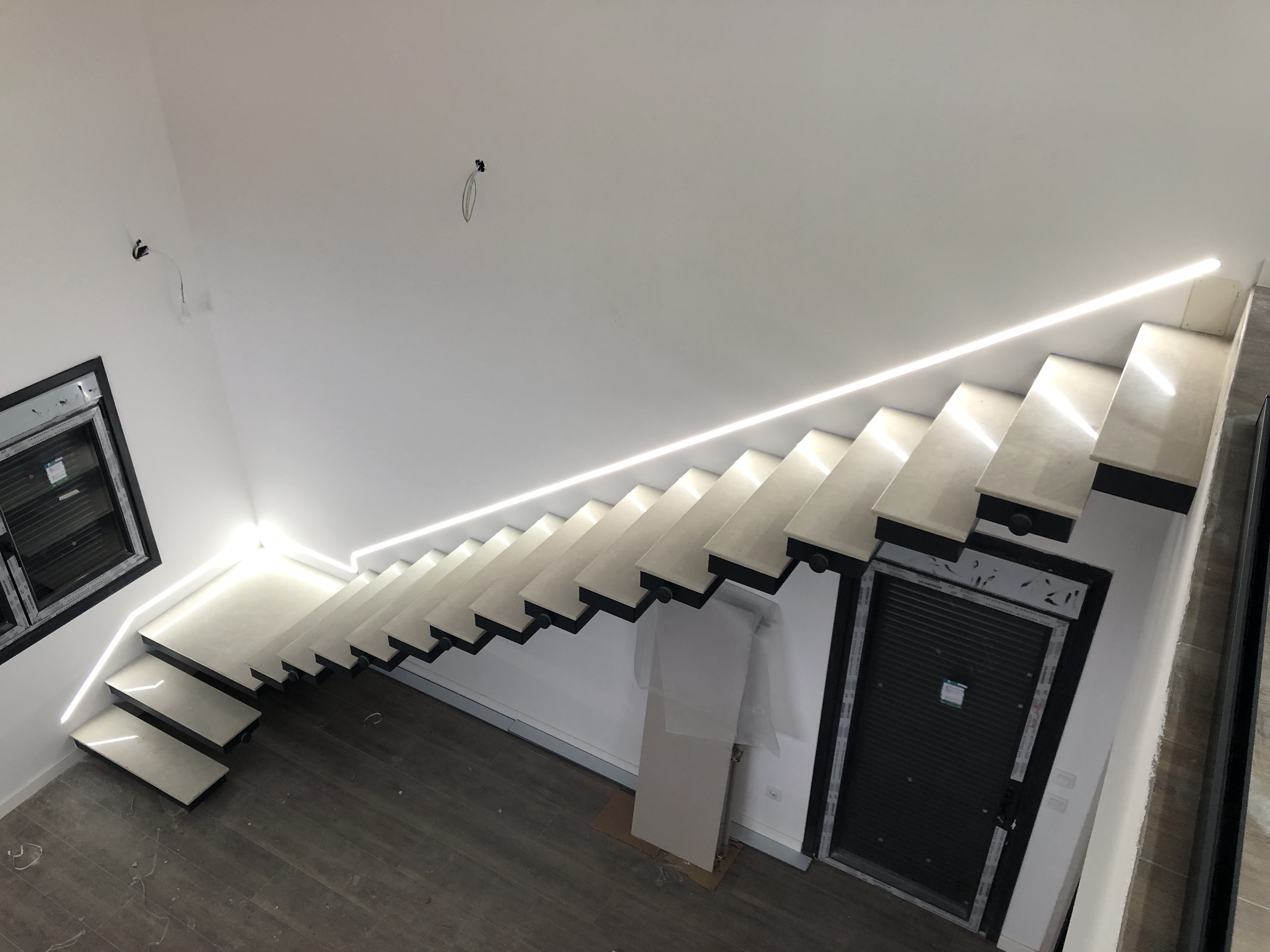 Iluminación LED lineal encendida junto a los peldaños de una escalera