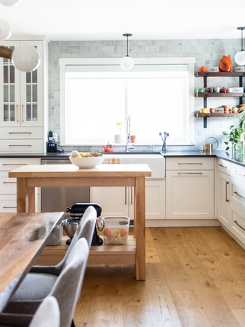 Renovated kitchen with full height wrap-around brick backsplash and apron sink overlooking front yard in Bridgeland Calgary bungalow by Kim Joy Design