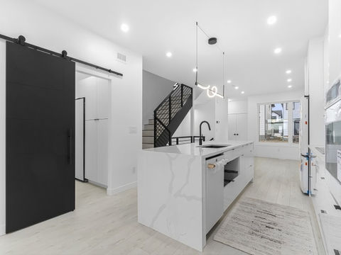 Modern kitchen in Touchstone custom home with crisp whites and clean lines. Kitchen features built in appliances and quartz waterfall island
