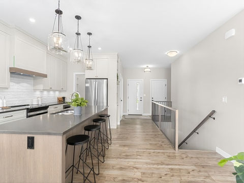 Gourmet white and wood kitchen with large island that seats 4. Custom range hood with wood trim and quartz that looks like soapstone lends a timeless elegance to the Touchstone Bungalow.