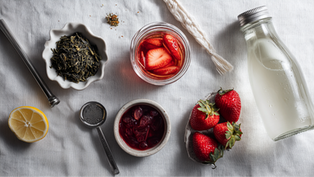 A clear glass pitcher of strawberry sparkling tea catching the light, effervescent bubbles rising, surrounded by whole strawberries, mint sprigs.