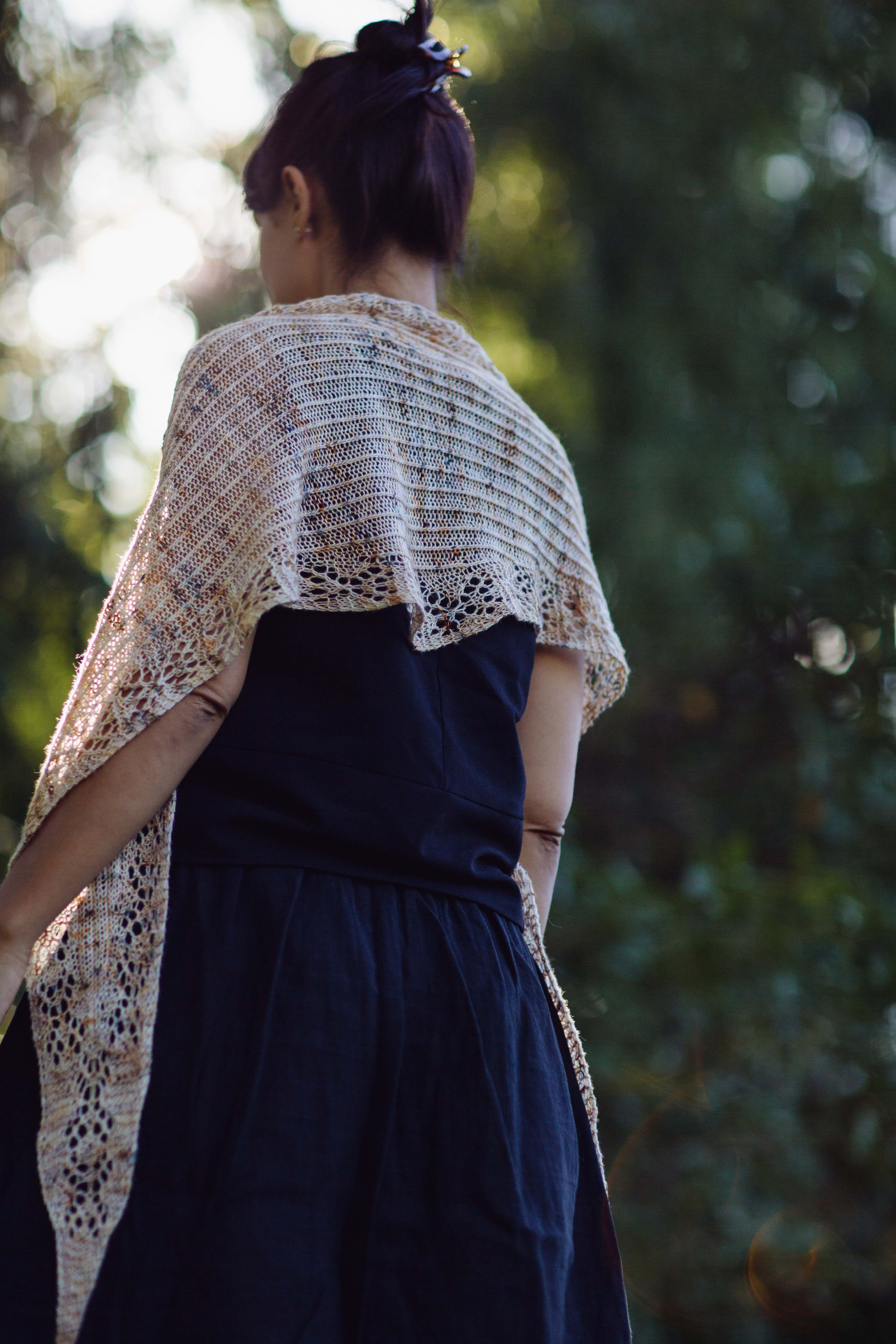 Back view of woman wearing diamond shaped shawlette. Handknit