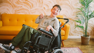 Young man with a disability smiling in a wheelchair at home, representing Florida families navigating SSI and SSDI benefits and Medicaid eligibility.