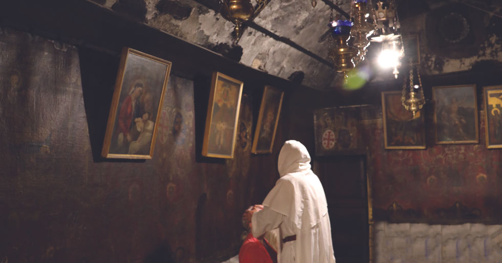 A priest praying over a person inside a cave.